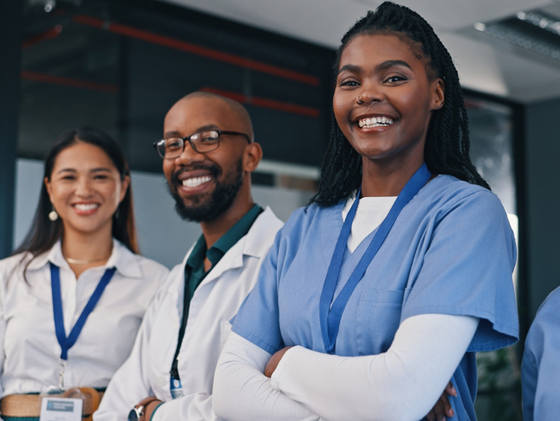 Friendly young nurse in white coat holding clipboard laughing with elderly female patient during homecare visit consultation